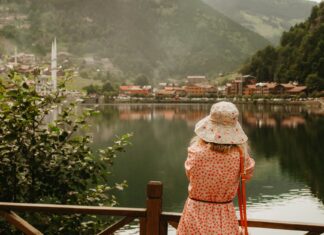 Kobieta w sukience nad jeziorem podziwia górskie miasteczko