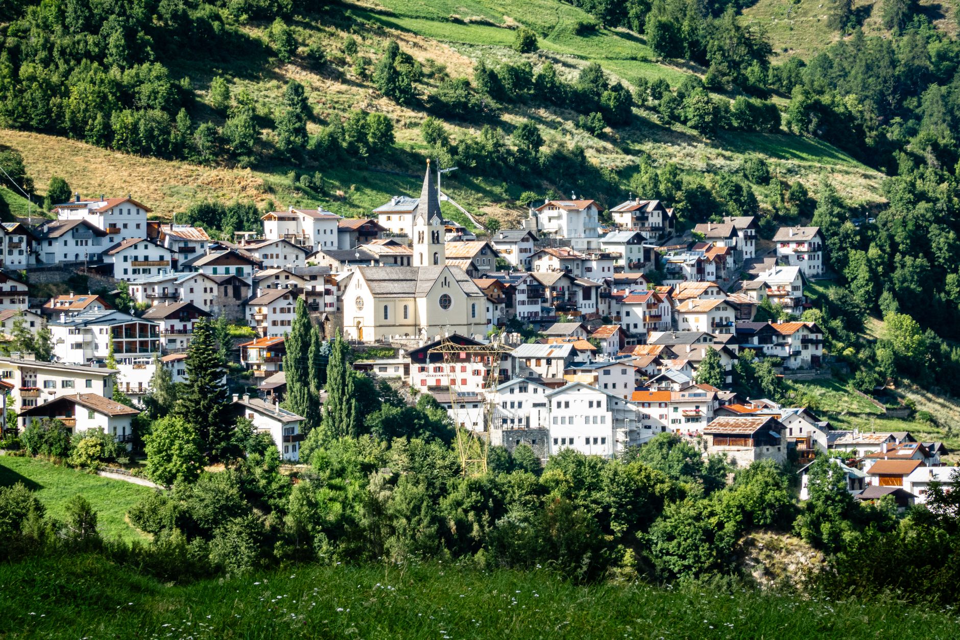 Malownicza alpejska wioska pośród soczyście zielonych wzgórz