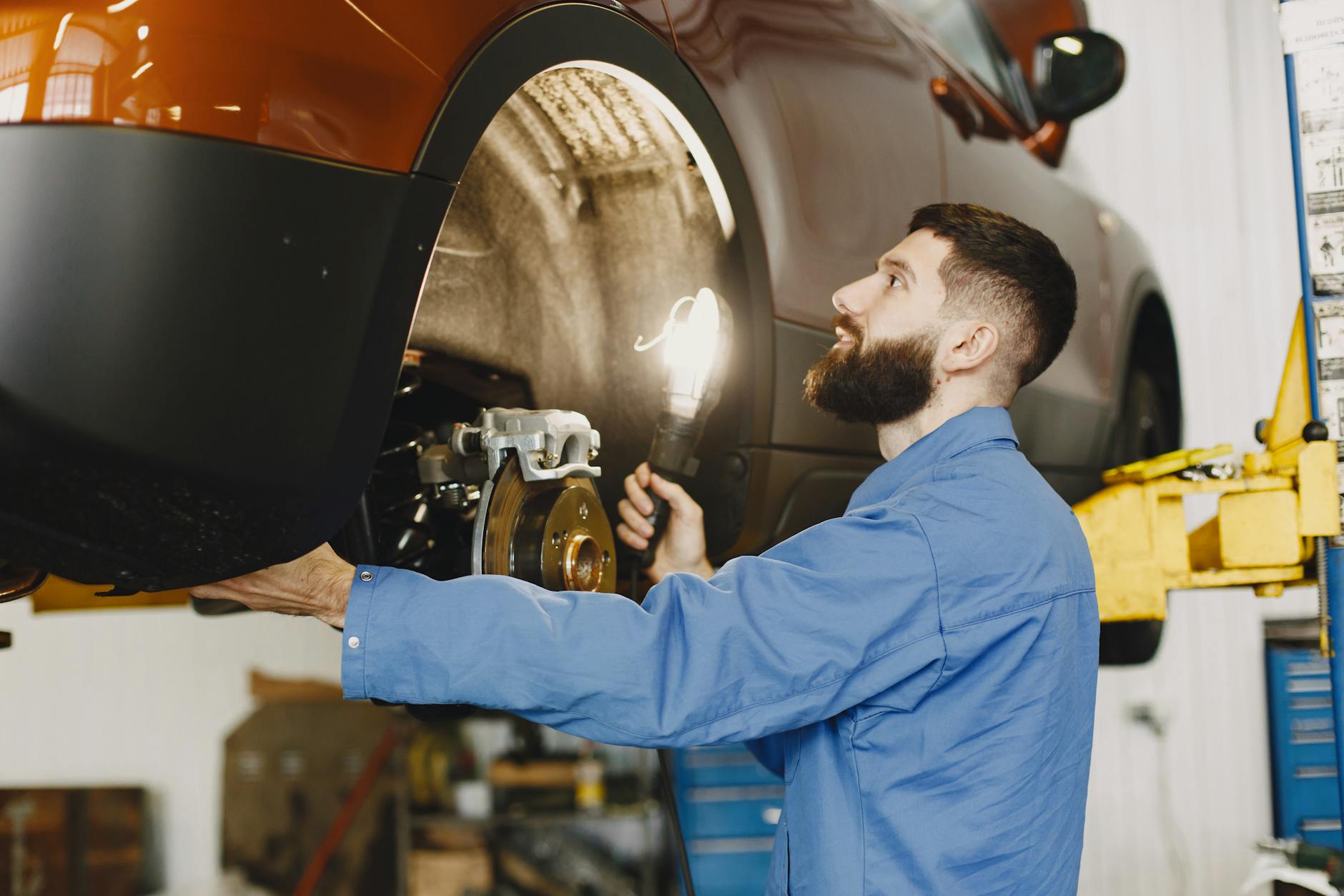 Mechanik w niebieskim kombinezonie sprawdza tarcze i klocki hamulcowe