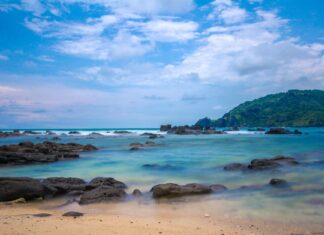 Najpiękniejsze plaże Malezji: porównanie wysp Perhentian, Redang i Tioman Tropikalna plaża w Malezji z kamienistym brzegiem i zielonym wzgórzem
