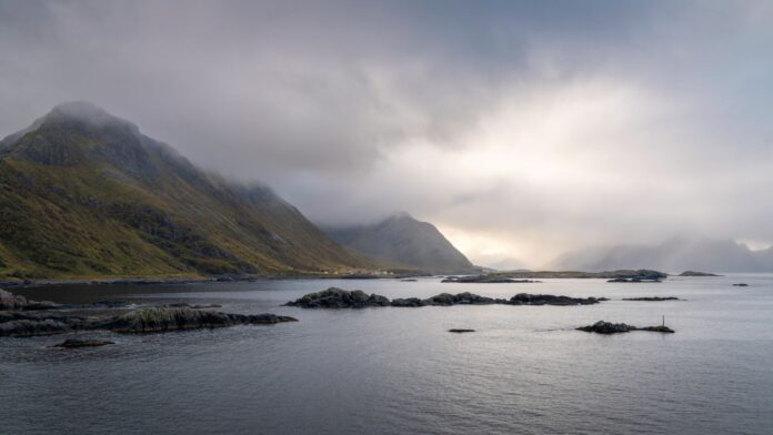 Mglisty fiord na Lofotach z górami i chmurnym niebem w Norwegii