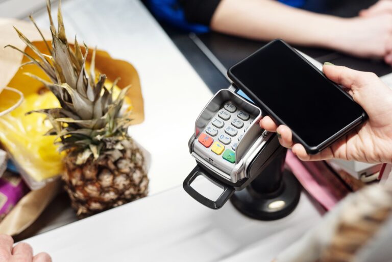 Zbliżenie na płatność zbliżeniową smartfonem przy kasie z ananasem
